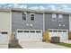 Rear exterior view of townhomes with white garage doors and gray siding at 3705 Rosebush Dr, Zebulon, NC 27597