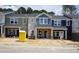 New townhomes showcase modern facades, each distinguished by varying siding colors and brick foundations at 3707 Rosebush Dr, Zebulon, NC 27597