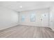 Bright living room featuring new hardwood floors, two windows, and a freshly painted white door at 3707 Rosebush Dr, Zebulon, NC 27597
