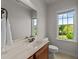 Bathroom features a single sink vanity, toilet, and a window with scenic views at 3832 Crimson Clover Ave, Wake Forest, NC 27587