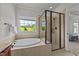 Bright bathroom boasts soaking tub, glass shower, and windows with view at 3832 Crimson Clover Ave, Wake Forest, NC 27587