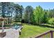 Beautiful backyard featuring a stone patio, fire pit with chairs, expansive lawn, and wooded area at 4001 Belmont Forest Way, Raleigh, NC 27606