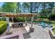 Inviting outdoor kitchen with stone accents, stainless steel grill, sink, and cozy fire pit with Adirondack chairs at 4001 Belmont Forest Way, Raleigh, NC 27606