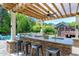 Outdoor kitchen with stone counter, overhead pergola, and bar seating overlooking a backyard with firepit at 4001 Belmont Forest Way, Raleigh, NC 27606