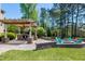 Backyard features a covered outdoor kitchen with stone accents and cozy fire pit with Adirondack chairs at 4001 Belmont Forest Way, Raleigh, NC 27606