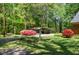 Beautiful backyard featuring mature trees, flowering shrubs, a charming swing, and a convenient covered parking area at 4298 Old Stage S Rd, Erwin, NC 28339