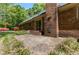 Brick home with sliding glass doors opening onto a brick patio, surrounded by lush greenery and blooming flowers at 4298 Old Stage S Rd, Erwin, NC 28339