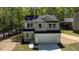 View of a newly constructed home with gray siding and a two car garage in a wooded area at 5022 Mockingbird Ln, Sanford, NC 27332