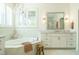 Luxurious bathroom with a chandelier, soaking tub, white cabinets, and a window with plantation shutters at 5265 Aleppo Ln, Raleigh, NC 27613