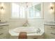 Bright bathroom with a soaking tub, white cabinets, marble counters and an abundance of light at 5265 Aleppo Ln, Raleigh, NC 27613