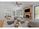 Bright living room featuring a stone fireplace, TV, hardwood floors, and sliding doors to the outdoor balcony at 5504 Spring Bluffs Ln, Raleigh, NC 27606