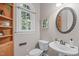 Powder room with pedestal sink, wood cabinet, and an arched window at 5504 Spring Bluffs Ln, Raleigh, NC 27606