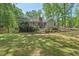 Well-manicured backyard with a spacious lawn, mature trees, and a charming home exterior at 6614 Chantilley Place, Bahama, NC 27503