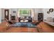 Open living area with hardwood floors, a comfortable sofa, and large windows overlooking the greenery at 6614 Chantilley Place, Bahama, NC 27503