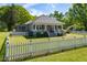 Charming gray home featuring a manicured lawn, a classic white picket fence, and a welcoming covered front porch at 7308 York, Mebane, NC 27302