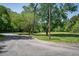 Well-manicured front yard with lush trees and a circular driveway on a sunny day at 861 Dalewood Dr, Raleigh, NC 27610