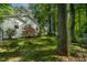 Landscaped fenced yard and white cottage-style home, shaded by mature trees at 107 Piquot Dr, Louisburg, NC 27549