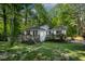 A fenced yard featuring a white cottage-style home and a green lawn surrounded by trees at 107 Piquot Dr, Louisburg, NC 27549