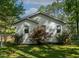 Landscaped fenced yard with white cottage-style home, accented by mature trees at 107 Piquot Dr, Louisburg, NC 27549