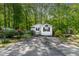 Quaint white cottage-style home with lush greenery, mature trees, and well-maintained yard at 107 Piquot Dr, Louisburg, NC 27549