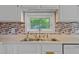 A stainless steel sink is framed by tiled backsplash, white cabinets, and a bright window at 107 Piquot Dr, Louisburg, NC 27549