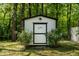 A shed with white painted walls and black trim is nestled among verdant bushes at 107 Piquot Dr, Louisburg, NC 27549