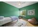 Green bedroom featuring wood floors, bed, area rug, and peaceful window view at 1101 Norris St, Raleigh, NC 27604