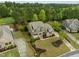 Aerial view of a brick and green home with mature landscaping, a long driveway, and a lush wooded backdrop at 1104 Covered Bridge Trl, Chapel Hill, NC 27517