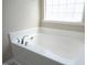 A close up of a clean and modern bathtub with chrome fixtures and a window for natural light at 1209 Redwood Valley Ln, Knightdale, NC 27545