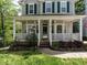 Inviting front porch with white columns and railing, stone-accented landscaping, and a well-maintained lawn at 207 Reedhaven Dr, Cary, NC 27513