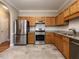 Spacious kitchen featuring stainless steel appliances, granite countertops, tile backsplash, and wooden cabinetry at 207 Reedhaven Dr, Cary, NC 27513
