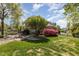 Brick home boasts a lush green lawn, blooming bushes, and lovely patio seating at 2545 Churchill Dr, Burlington, NC 27215