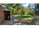 This view shows a brick exterior of the home and a grassy backyard with mature trees at 2605 Joe Pruitt Rd, Oxford, NC 27565