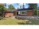 Quaint brick home with stone accents, a classic black front door, and mature trees at 2605 Joe Pruitt Rd, Oxford, NC 27565
