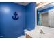 A bright bathroom with an anchor on the blue wall, a mirror, and a sink with cabinet storage at 305 Freeman St, Raleigh, NC 27601