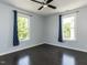 Bedroom features hardwood floors, blue walls, two windows with blue patterned curtains, and ceiling fan at 314 Gray Ave, Durham, NC 27701