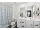 Well-lit bathroom with a double sink vanity, white cabinets, neutral paint and a shower with a patterned curtain at 390 Hunting Wood Dr, Angier, NC 27501