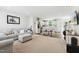 Bright living room featuring a comfortable gray sofa, neutral carpeting, and an open floor plan to the kitchen at 390 Hunting Wood Dr, Angier, NC 27501