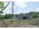 View of a home's backyard with lawn, trees, and a screened-in porch on a sunny day at 395 Carolina Landing Dr, Zebulon, NC 27597