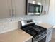 Modern kitchen features stainless steel appliances, gray cabinets, and light quartz countertops at 4004 Silver Oak Ln, Durham, NC 27703