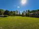 Large, sunny lawn on a property with mature trees and partial view of a brick home at 4170 Buckhorn Rd, Sanford, NC 27330
