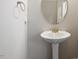Stylish half bathroom featuring a pedestal sink with a silver faucet, oval mirror, and a towel ring at 419 E East Hinton St, Clayton, NC 27520