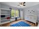 Bright bedroom featuring a crib, built in window seat, shelving unit, and a ceiling fan at 504 Cameron Glen Dr, Apex, NC 27502