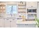 Bright kitchen featuring stainless steel appliances, white cabinets and floating wood shelves at 918 Orient St, Durham, NC 27701