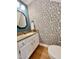 Charming powder room with patterned wallpaper, granite countertop, and stylish black framed mirror at 1002 Springmill Ct, Apex, NC 27502