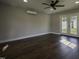 Spacious living room featuring dark laminate flooring, bright double doors, and a ceiling fan for added comfort at 101 Pine St, Dunn, NC 28334