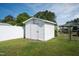 White storage shed in a sunny backyard with a white fence and green grass at 101 Pine St, Dunn, NC 28334