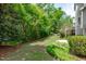 Lush backyard featuring green grass, various plants and trees, and a stone patio at 103 Woodland Ridge Ct, Cary, NC 27519