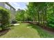 Lush backyard featuring a well-maintained lawn, mature trees, and partial view of the home's exterior at 103 Woodland Ridge Ct, Cary, NC 27519