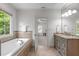 Bathroom featuring a soaking tub beneath a window and double vanity with granite counters at 103 Woodland Ridge Ct, Cary, NC 27519